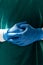 Vertical of midsection of surgeon in blue gloves and green gown, with copy space