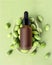 Vertical mockup of beauty oil bottle with black pipette cap on green background, exotic fruit. Frosted brown vial of emulsion,