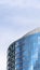 Vertical Moden building with glass walls and balconies viewed against cloudy blue sky