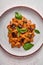 Vertical orientation pasta farfalle with eggplant, tomato sauce, cheese and basil on plate