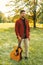 Vertical outdoors portrait of a young man holding an acoustic guitar on grass.