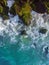 Vertical overhead aerial shot of a wavy blue sea against the rocks