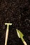 Vertical overhead of miniature gardening trowel and rake on soil with fertiliser, with copy space