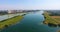 Vertical panorama of fantastically beautiful landscape with stretching narrow river and forest shore on background of metropolis