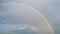 Vertical panorama. Rural landscape, rain clouds and rainbow