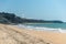 Vertical panorama of the seacoast of the personless Taipe beach, with brown seaweed in the harsh sand, a blue ocean and