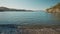 vertical panoramic filming of beautiful calm turquoise sea water at wild solitary pebble beach with cliffs at coast of