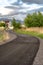 Vertical Paved road with yellow traffic delineator posts winding through a grassy field