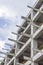 Vertical perspective shot of construction of a new reinforced concrete and metal beams linked building with open blue sky