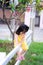 Vertical photo of an Asian girl aged 3 years old climbing a white fence to jump to the other side.