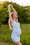 Vertical photo of a beautiful pregnant woman with a great figure on a natural background. A happy pregnant woman in slinky white