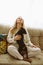 Vertical photo of blond woman hugging her best friend, black dog on sofa. Relaxing and cuddling. Animal communication