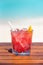 Vertical photo of dry negroni cocktail with straw on wooden table at the beach