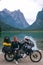 Vertical photo. Girl motobiker in protective turtle jacket stands with touring motorcycle. Extreme travel vacation, motorcyclist