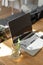 Vertical photo of laptop on wooden home table in kitchen, plants in water and sunny morning light. Cottagecore concept