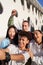 Vertical photo of a Latin guy taking a selfie with a multiracial group of people. Happy students together on