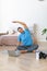 Vertical photo of a middle aged man during online steaming. Home yoga workout - stretching back.