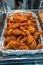 Vertical photo of pile of fried chicken drumsticks at market