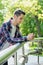 Vertical photo portrait of cheerful nice handsome positive glad person leaning on railing sending notification to girlfriend