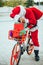 Vertical photo of santa claus supported in a bicycle full of gifts with exhausted expression