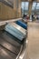 Vertical photo of silver colored suitcase on luggage conveyor belt