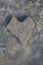 Vertical photo of a stone heart with a yellow lichen on a background, beautiful rock nature creation