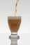 vertical photo of a stream of beer falling into a glass on a white background