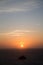 Vertical photo of sunset with rock in the middle of the sea.