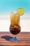 Vertical photo of tropical brown color cocktail with lime on the wooden table at the beach with ocean
