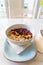 Vertical photo of a typical brazilian açaí bowl with cereals, different berries and edible flowers