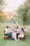 The vertical photo of the wedding dinner with the newlyweds and guests celebrating the ceremeny in the sunny forest.