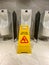 Vertical photo of wet floor alert sign in public male toilet