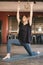 Vertical photo of young adult female yogi new teacher practicing yoga with eyes closed, arms extended, knee on floor, barefoot