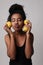 Vertical photo of young woman posing with three parts of lemon on white wall.