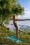 Vertical photo of a young woman standing in an asana by the river