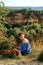 Vertical picture of beautiful short haired woman sitting at edge of gorge near one of the most beautiful villages of France