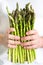 Vertical picture of bundle of green asparagus in hands of man. Mens hands pick bunch of fresh asparagus. Healthy food, vegan,