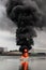 Vertical picture of a burning boat with heavy smoke on the water under a cloudy sky at daytime