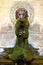 Vertical picture of decorative fountain with lion head overgrown with moss and fern with clear water in Lourmarin, one of most