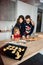 Vertical picture of family with little daughter cooking baking pastry, pie at home together, parents enjoy weekend play doing