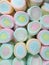 Vertical picture of lined up pastel pink, yellow, blue colored marshmallows