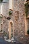 Vertical picture of medieval stone narrow street in small italian town in Veneto with vintage lanterns and flowers in windows.