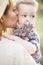 Vertical picture of mother holding her child on hands. She is kissing him