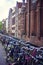 Vertical picture of old brown bricky dutch buildings in Amsterdam, Netherlands with a lot of bicycles in front of them. Typical