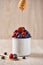 Vertical picture of a white bowl full of blueberries and strawberries with dripping honey