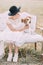 The vertical portrait of the bride petting the cute fluffy dog while sitting on the white old-fashioned sofa in the