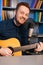 Vertical portrait of cheerful guitarist singer man playing on acoustic guitar and singing into microphone recording song