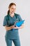 Vertical portrait of cheerful young woman doctor in medical uniform writing prescription on clipboard, fills out medical