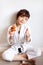 Vertical portrait of cute 7 years old hungry short haired girl in white kimono eating pizza after hard on-line karate taekwondo