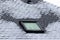 A vertical portrait of a frozen slate roof with a skylight window which is also frozen during winter time. At the sides of the